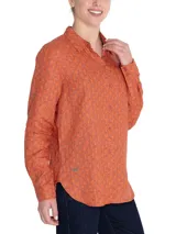 Blusa de manga larga confeccionada en lino orgánico, con cuello camisero y cierre frontal de botones. Presenta un estampado integral de motivos marinos en tonos rojizos y burdeos, con un bolsillo superior en el pecho.