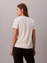 Remera Calvin Klein de punto de algodón regenerativo, color beige melange, de corte regular y manga corta con vuelta. Presenta cuello redondo y sutil logo bordado en el pecho.