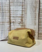 Neceser color arena con detalles en cuero marrón y etiqueta de cuero con logo de la marca.