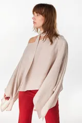 Blusa de lino italiano color negro, con diseño asimétrico de hombro descubierto y cuello tipo choker integrado, de manga larga amplia.