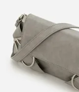 Cartera tipo baguette de tamaño pequeño, confeccionada en poliuretano con acabado estructurado. Presenta una solapa frontal con detalles de hebillas decorativas metálicas, correa para el hombro y un compartimento interior forrado.