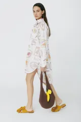 Camisa de manga larga, corte holgado, color blanco, con estampado de frutas y verduras en tonos pastel y terrosos, con texto en español.