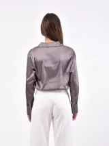 Camisa color beige de manga larga con cuello clásico y cierre frontal con botones.