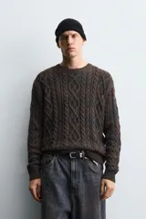 Jersey de punto con diseño de trenzas, cuello redondo y manga larga. Presenta un acabado en rib en puños y ruedo, con un efecto de lavado que le otorga una apariencia única.