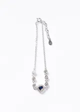 Pulsera de plata 925 con cadena de eslabones finos, decorada con piedras de zirconia transparentes engarzadas y un dije central en forma de corazón con una zirconia azul marino rodeada de pequeñas piedras brillantes.