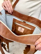 Bolso tipo tote Chabas modelo Molly, confeccionado en cuero con pelo natural en tonos marrón y blanco. Posee asas largas de cuero marrón, parche frontal con la marca grabada y un charm colgante decorativo en forma de estrella con detalle de pelo.
