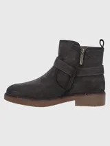 Bota corta de descarne color marrón oscuro, con diseño de caña media y cierre lateral. Presenta una tira decorativa con hebilla metálica en el tobillo y suela de goma tipo plataforma con textura rugosa.
