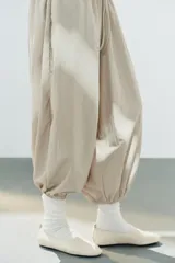 Bailarina plana de piel en color blanco, con tirador trasero, detalle elástico en el empeine y suela plana.