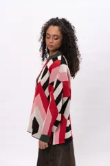 Buzo de tejido de punto con diseño geométrico multicolor en tonos rojo, rosa, negro y beige. Presenta cuello redondo y puños en color verde oscuro.