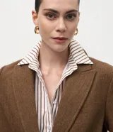 Blazer femenino de corte regular confeccionado en polivelour con textura de espiga. Presenta solapa clásica, mangas largas, cierre frontal con botones y bolsillos funcionales.