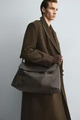 Bolso tipo bandolera de gran tamaño fabricado en piel con acabado grabado. Cuenta con un compartimento principal con cierre de solapa magnética y cremallera, además de bolsillos interiores. Incluye un asa de hombro ajustable en piel.