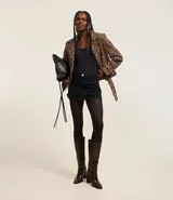 Minifalda de jeans negra con cintura media, trabillas, bolsillos y cierre frontal con botón y cremallera.