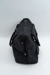 Bolso de viaje tipo duffle, color negro, con cierre principal superior, bolsillo frontal con cierre y doble asa de mano.