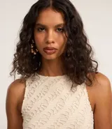 Vestido midi de crochet color crudo, sin mangas y con cuello redondo. Presenta aberturas laterales en el ruedo.