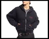 Campera negra de algodón con cierre frontal, capucha, bolsillos laterales y detalles de tachas metálicas en la capucha y los bolsillos. Presenta un estampado frontal con texto en tono rojizo.