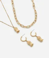 Conjunto de bijouterie compuesto por dos collares en capas y un par de aros tipo argolla con dije de flor. Uno de los collares presenta eslabones ovalados, mientras que el otro es una cadena fina con pequeñas esferas y un dije central de flor en relieve. Los aros incluyen el mismo diseño de dije floral colgante.
