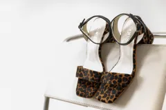 Sandalias de taco ancho con estampa animal print de leopardo, tira delantera ancha y tira fina ajustable al tobillo de color negro.