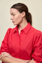 Camisa de algodón blanca con cuello camisero, frente abotonado y mangas abullonadas de corte relajado.