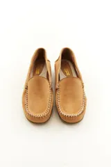 Mocasines de cuero vacuno color beige con acabado mate, costuras visibles artesanales en el empeine y suela de perfil bajo.