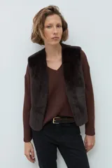 Chaleco reversible de corte recto, con un lado de cuero sintético color chocolate y el otro lado de piel sintética al tono. Presenta cuello redondo y diseño sin mangas.
