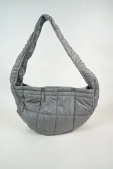 Cartera tipo hobo de diseño acolchado con costuras cuadradas, confeccionada en material sintético de acabado satinado. Cuenta con un asa única integrada y cierre mediante botones a presión en la parte superior.