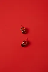 Aros tipo caravanas con diseño de doble piedra de resina en tonos ámbar y marco metálico dorado.