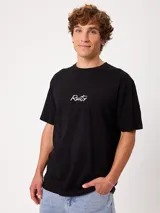 Remera blanca Rusty de corte holgado, con cuello redondo y mangas cortas. Presenta un estampado en la espalda de estilo veraniego con palmeras, una tabla de surf y letras alusivas a la marca.