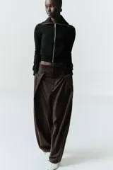 Chaqueta de felpa negra con cuello solapa, manga larga con puño, bolsillos de plastrón en el delantero y cierre frontal con cremallera.