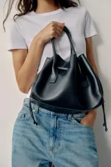 Bolso tipo shopper de cuero sintético en color azul oscuro, con diseño fruncido, doble asa de mano y cordones ajustables a los lados.