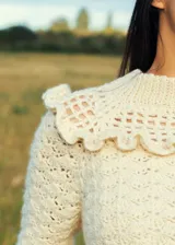 Sweater color crema tejido a crochet con lana merino, cuello alto con volados y mangas largas.