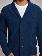 Cárdigan de punto azul con diseño de ochos, cuello smoking y cierre frontal con botones. Presenta un acabado jaspeado con motas de colores.