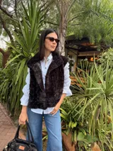 Chaleco de piel sintética color negro, diseño reversible con interior de tela bordada, corte recto y sin mangas.