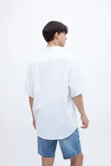 Camisa de manga corta color celeste claro, con cuello solapa clásico y bolsillo en el pecho. Presenta una textura ligera y un calce regular.