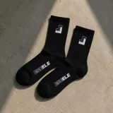 Medias negras de caña alta con diseño acanalado, elástico superior y detalles estampados en blanco que incluyen el logo en el empeine y el lateral.