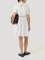 Vestido midi de lino orgánico y viscosa en color blanco, con cuello mao, mangas cortas y cierre frontal con botones. Presenta detalles de encaje en los hombros, el pecho y la cintura, además de forro interior a tono.