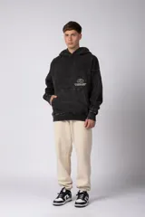 Buzo canguro oversize de algodón frizado con efecto gastado, capucha y bolsillo frontal tipo canguro. Presenta estampa gráfica sutil en el pecho.