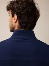 Campera de estilo safari en color azul marino, confeccionada en algodón. Presenta cuello alto, cierre frontal con cremallera y cuatro bolsillos delanteros con solapa y botones metálicos.