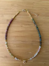 Collar corto de cuentas de turmalina multicolor con detalles de cuentas doradas y dije de sol dorado.