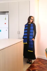 Bufanda de punto de gran tamaño, con diseño de rayas horizontales en azul y negro, y detalles en amarillo en los extremos.