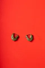 Aros tipo argolla de diseño escultórico y asimétrico, combinando metal dorado con resina en tono marmolado claro.