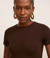 Blusa color beige de mangas cortas, confeccionada en tejido rib con textura acanalada y cuello redondo.