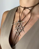 Collar de alpaca con colgante geométrico abstracto y tiento de gamuza marrón con apliques metálicos.