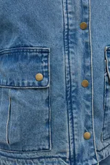 Campera de jean en tono azul medio, con cuello de pana en color marrón, cierre frontal con botones metálicos y bolsillos frontales tipo cargo.