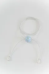 Gargantilla tipo bolo tie con cordón plateado trenzado, un dije central esférico en color celeste con incrustaciones de strass y perlas de río en los extremos.