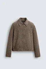 Cazadora de corte relajado confeccionada en tejido jacquard con textura. Presenta cuello solapa, cierre frontal con cremallera, mangas largas con puños abotonados y bolsillos de vivo en la cadera.