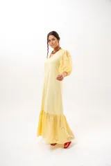 Vestido largo amarillo mantequilla con escote en V, mangas abullonadas y volados en el bajo con detalles de broderie.