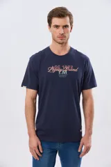 Remera azul marino de manga corta con cuello redondo, confeccionada en mezcla de algodón y poliéster. Presenta un diseño en el frente que combina estampa y bordado con la leyenda "Legacy Brand 1972" en tonos rosado, verde y marrón.