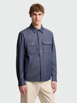 Camisa Moncler de jean azul oscuro, de manga larga, con cierre frontal de botones a presión, cuello clásico y dos bolsillos delanteros con solapa y botón.