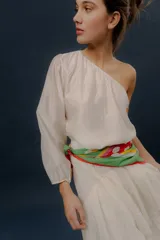 Blusa blanca de un solo hombro con manga larga abullonada y diseño holgado.