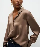 Camisa de satén color marrón chocolate, con cuello inglés, cierre frontal con botones y mangas largas con puños abotonados. Presenta un diseño fluido y acabado brillante.